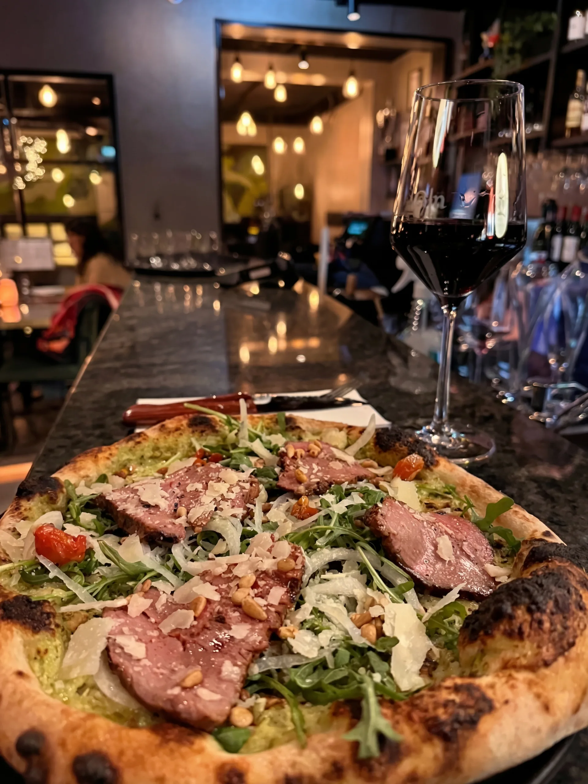 Gourmetpizza med prosciutto och vin i restaurangmiljö